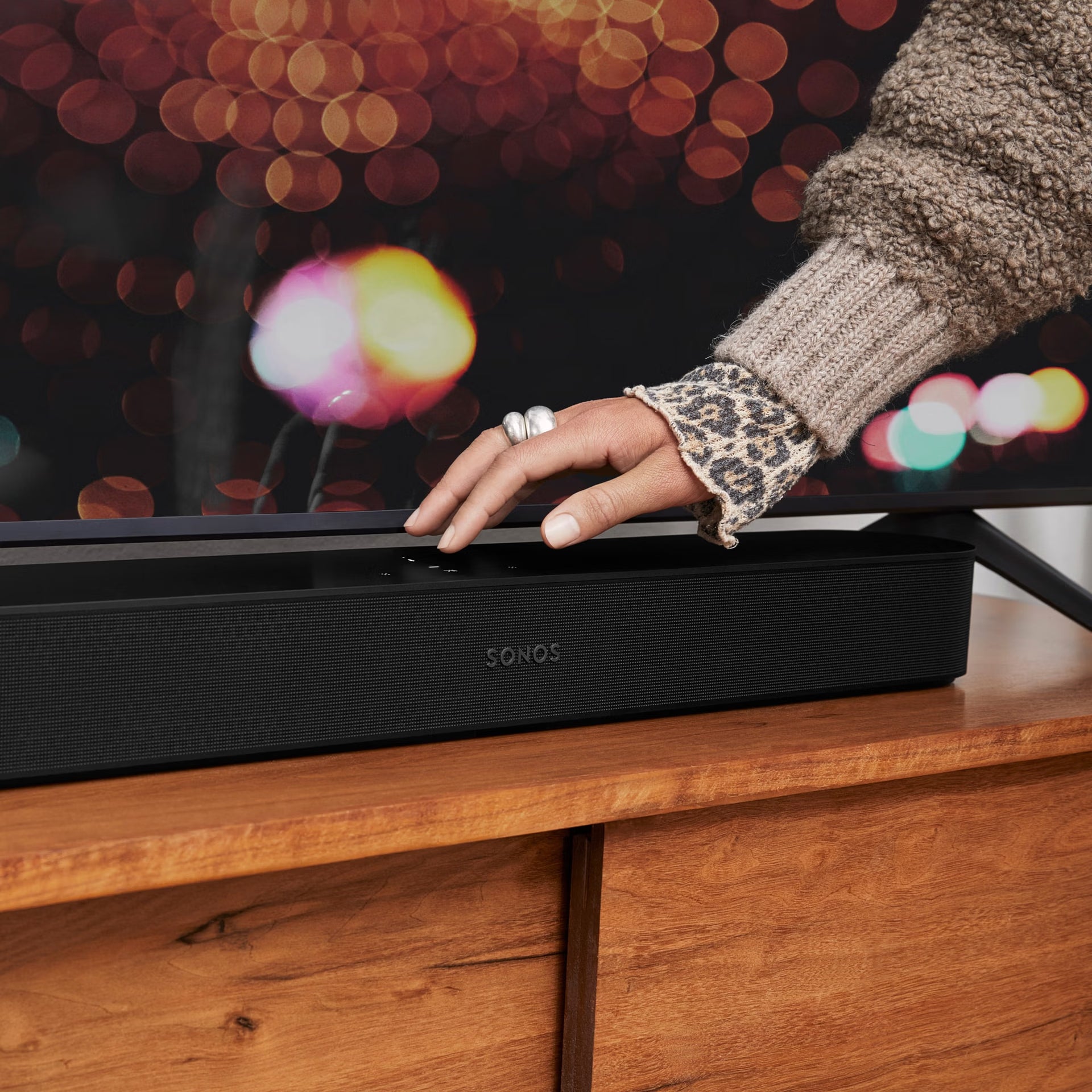Sonos Beam Gen 2 black below wall-mounted TV in modern living room — compact Dolby Atmos smart soundbar