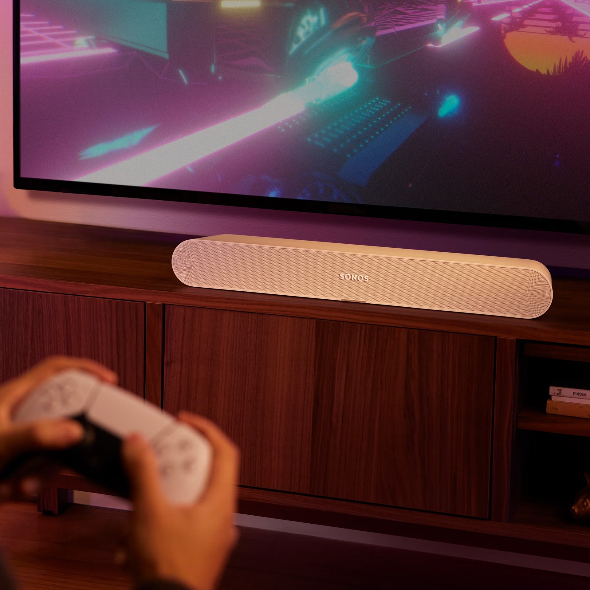 Person holding a remote control in front of a television with a Sonos soundbar.
