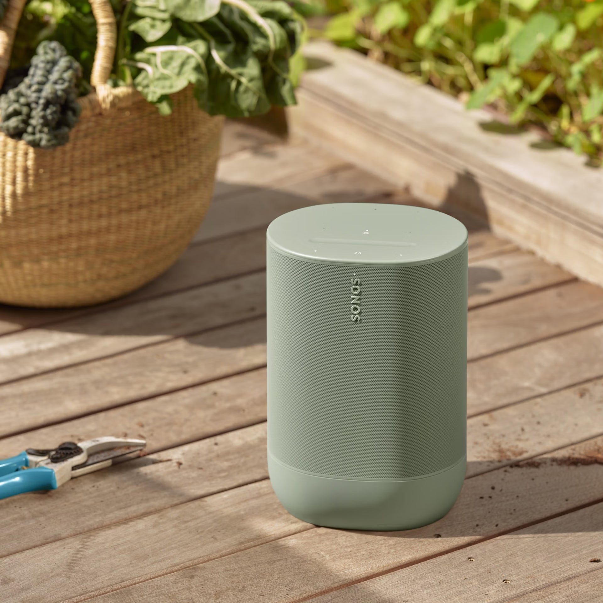 Sonos Move 2 Olive on a garden table delivering powerful HiFi sound in an outdoor setting