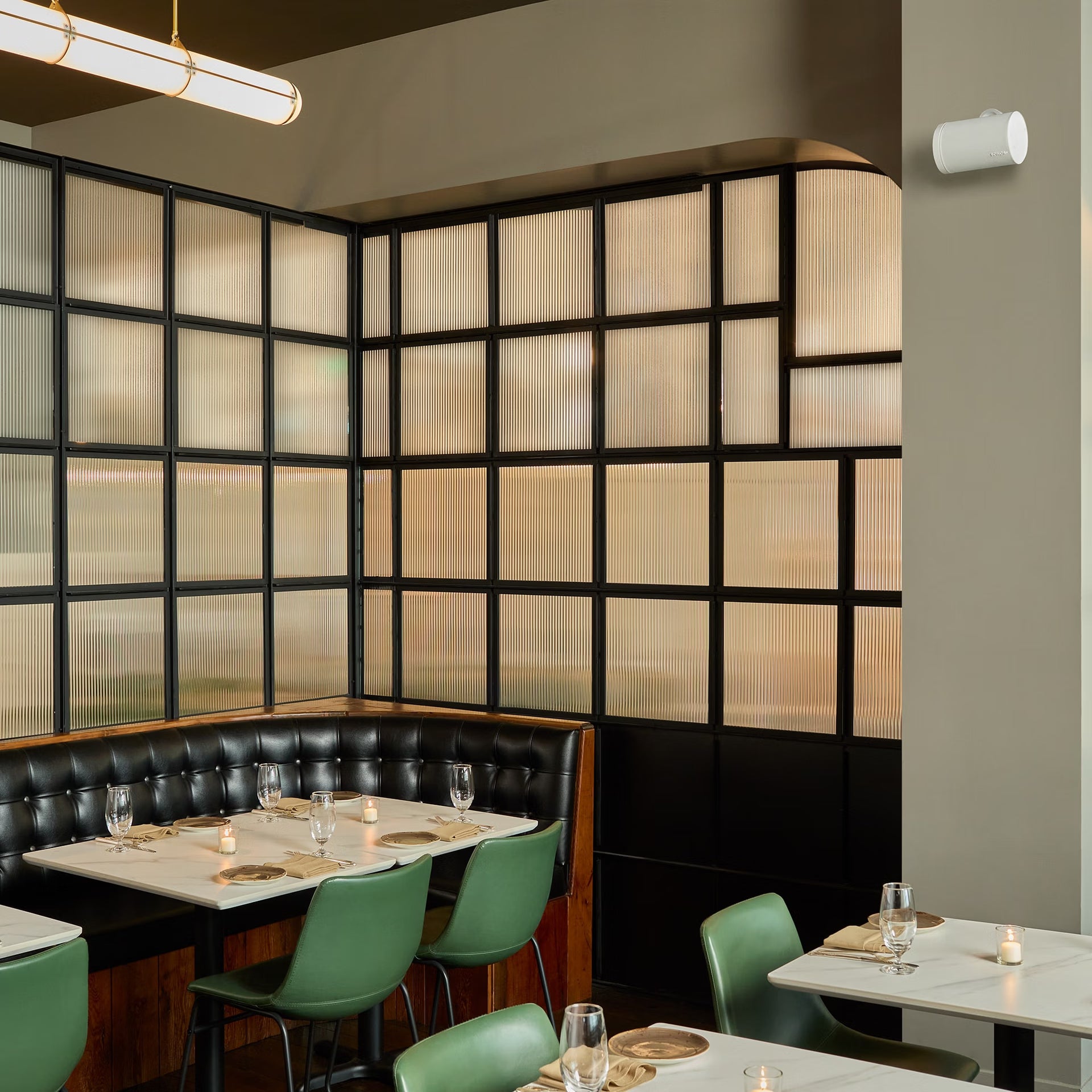 Dining area with tables, chairs, a wall with glass panels and Sonos Sonos Era 100 Pro (White)