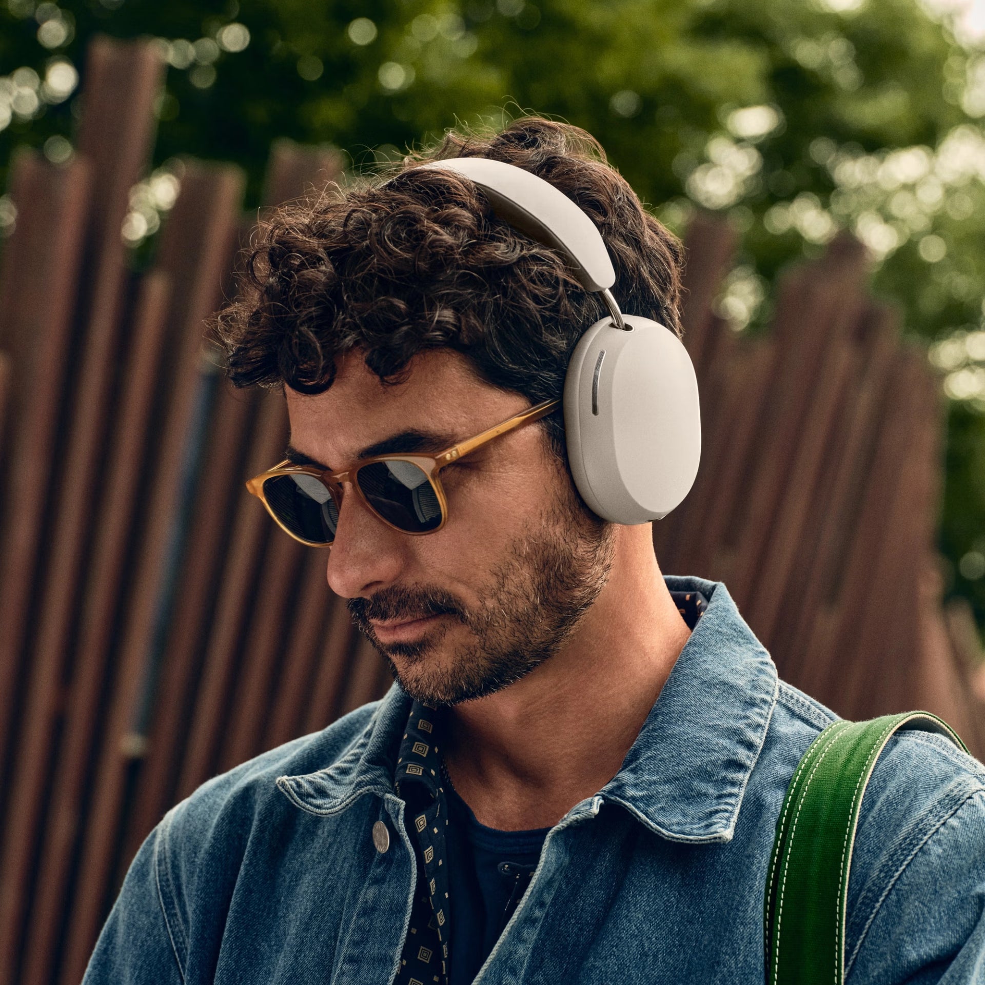 Man wearing  Sonos Ace White Wireless headphones and sunglasses with a blurred background